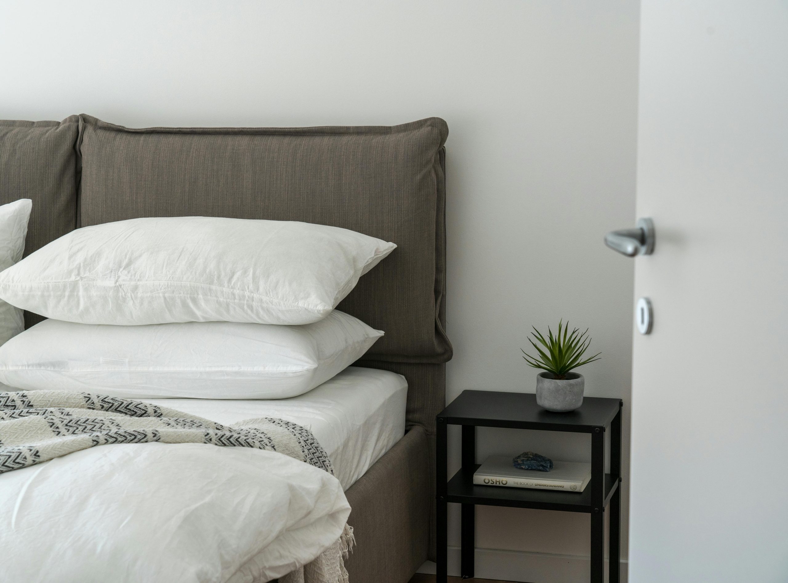 A serene and stylish bedroom featuring a comfortable bed with clean white bedding and a side table with decor.
